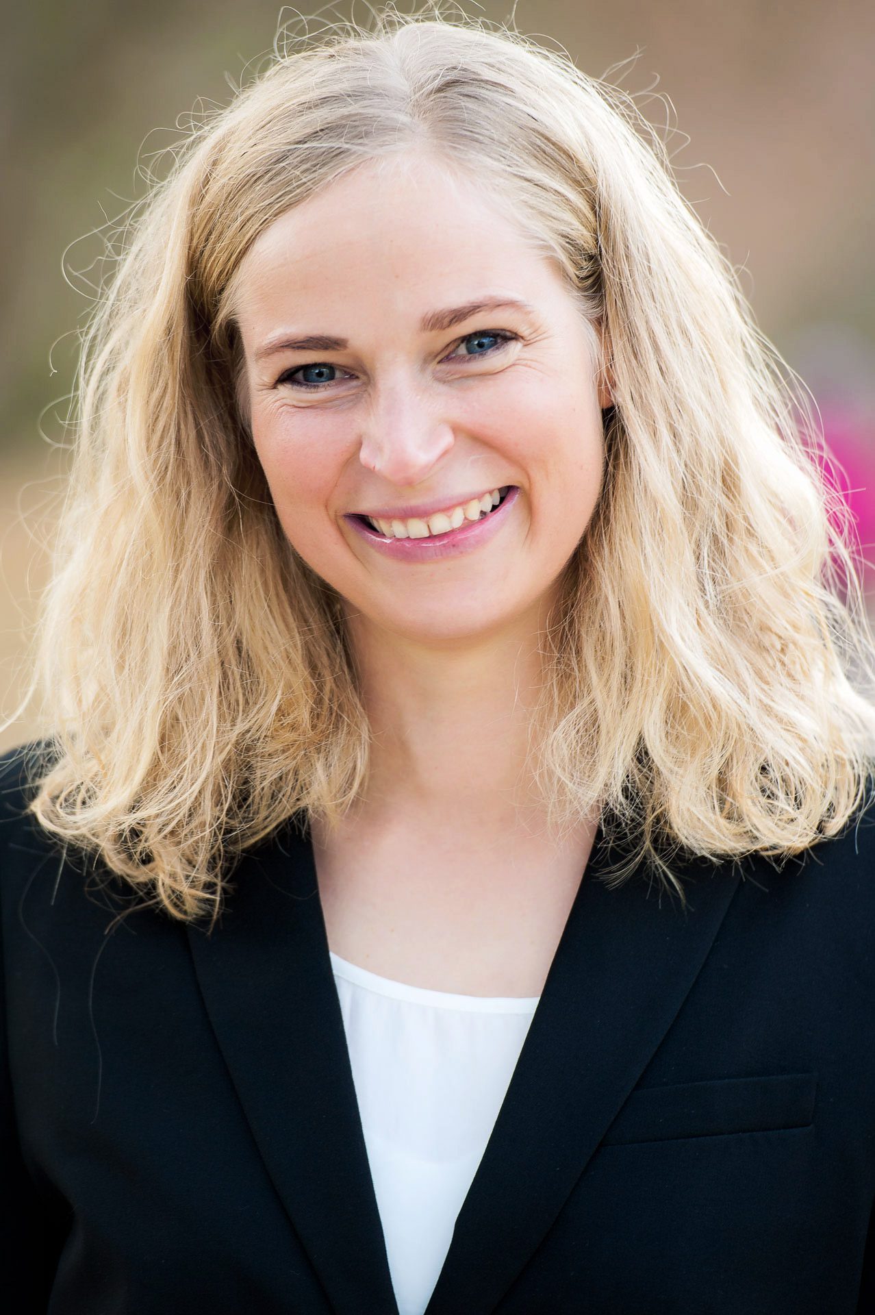 Lächelnde Frau mit blonden Haaren im Business-Outfit